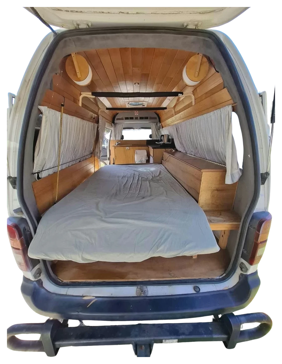 Looking into Hank through the open tailgate: bed, side cabinet, kitchen bench and timber-lined walls and ceiling